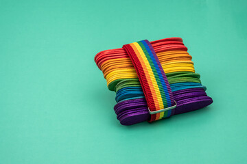 Rainbow of a group of popsicle sticks held together with a rainbow colored ribbon, on a green table. Pride day. 