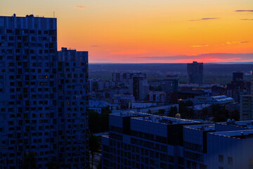 Fototapeta premium Cloudy rose blue sunset over dark silhouettes of city buildings, top view. Evening view.