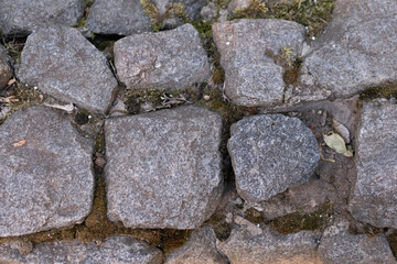 Road from large dark stones of cobblestones underfoot, texture, background