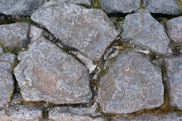 Road from large dark stones of cobblestones underfoot, texture, background
