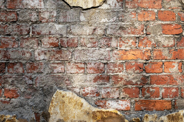 Close-up front view background fragment of an old red brick wall with traces of plaster. Selective focus.