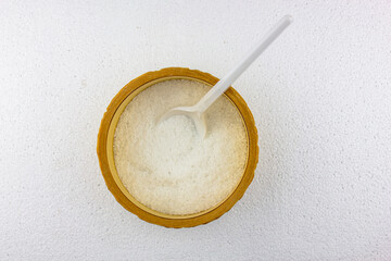 Salt in a wooden bowl with a white spoon on a white background. Table salt on the kitchen table.