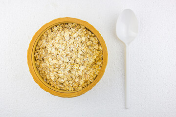 Oatmeal in a wooden bowl with a white spoon on a white background. Oatmeal cereal groats oats in a wooden box and a spoon on a white table