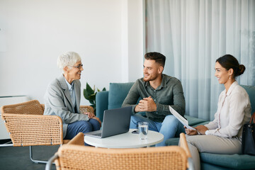 Young happy couple talking to financial advisor during meeting in the office.