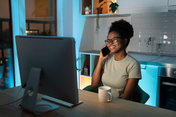 Happy african woman freelancer in glasses working remotely in cozy home office with houseplant on...