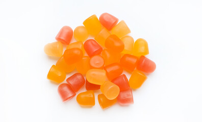 Close-up texture of orange and yellow multivitamin gummies in the form of bears on white background. 