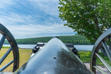Closeup of a historic black powder cannon standing guard over a shoreline