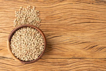 Raw lentils on a bowl over wooden table with copy space