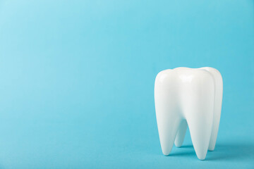 White tooth model on a blue wooden background. The concept of dental hygiene. Prevention of plaque and gum disease.MOCKUP