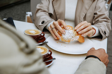 Couple in love drinking coffee and eating croissants at a table on the outdoor terrace of a cafe