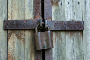 Rusty locked padlock on wooden door