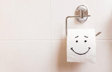 a roll of toilet paper with a happy face hanging on a white wall in the bathroom