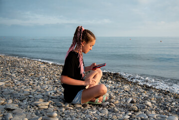 Fototapeta na wymiar The girl sits and communicates online. Communication. Generation Z. Recreation. Sea.