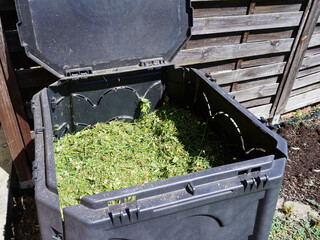 Kompostbehälter im Garten mit Rasenabschnitt