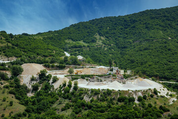 Fototapeta na wymiar Quarry for extraction of minerals with equipment and machines, and road, in Rhodope Mountains covered with forests