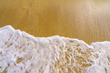 sea wave foam on golden sand, close up