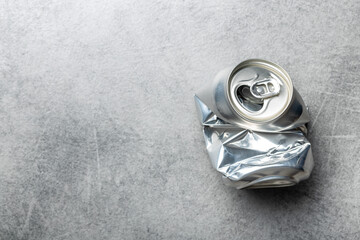 Empty crumpled can on gray table.