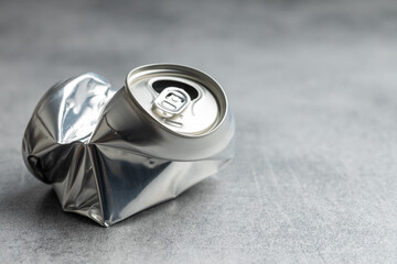 Empty crumpled can on gray table.