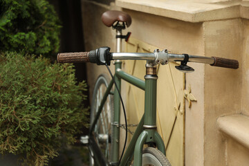 Fototapeta na wymiar Green bicycle parked near building, closeup view