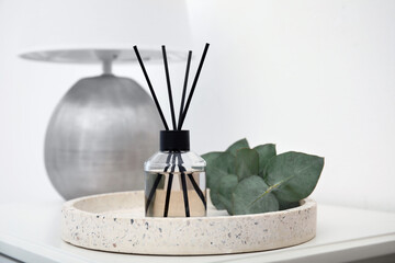 Reed diffuser with lamp and eucalyptus on white table, closeup