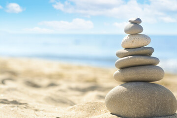 Stack of stones on sandy beach, closeup. Space for text