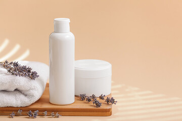 Fototapeta na wymiar Spa. Jar with moisturizing body cream, bath towel, lavender flower on beige background. Skin care cosmetic concept. Minimal style composition, copy space.