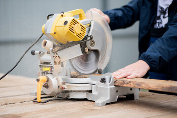 The man works with trimming saw. He is wearing a welder's protective mask and protective gloves. A rare working profession.