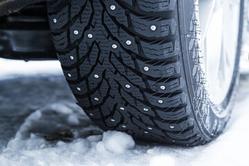Closeup of car winter tire with spikes in cold snow conditions - Powered by Adobe