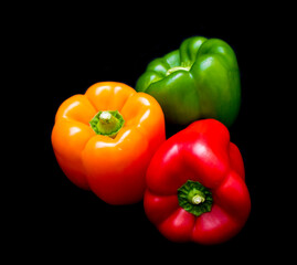 three different colored peppers: red, green and yellow peppers lie on a black background