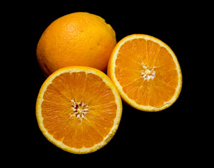 the whole and cut orange lies on a black background