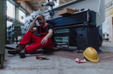 Fototapeta na wymiar Worker suffering from pain after accident in factory. First aid support on workplace concept.