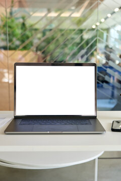 Workplace With Laptop Pc Computer And Cellphone On Desk With Blank White Empty Mockup Screen For Advertising In Modern Contemporary Office. No People. Business Concept. Vertical.