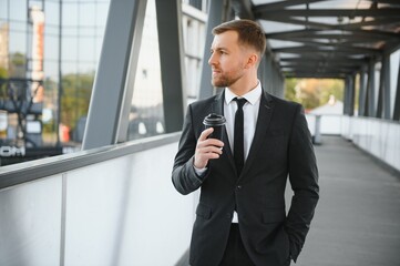 Close up serious businessman drinking take away coffee at street. Portrait of business man waiting with coffee to go outdoor. Office employee looking away at street. Male professional take break