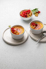 Creme brulee, cream brulee, burnt cream with currant in ramekins. Traditional french vanilla cream dessert with caramelised sugar on top. Homemade dessert with berries. Copy space. Selective focus.