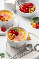 Creme brulee, cream brulee, burnt cream with currant in ramekins. Traditional french vanilla cream dessert with caramelised sugar on top. Homemade dessert decorated berries. Selective focus.
