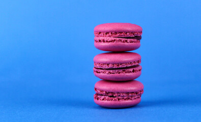 Fototapeta na wymiar Three pink macaroons on a blue background