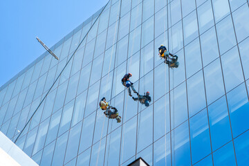 Window cleaners is working on the high rises office building facade