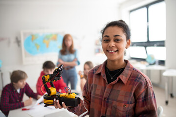College student holding her robotic toy at robotics classroom at school.