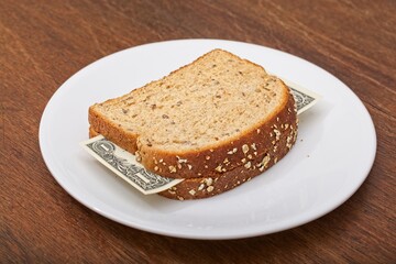 'Consumer staples inflation concept of US dollar bill sandwich with whole grain bread slices on dinner plate'