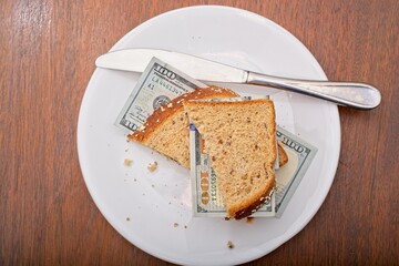 'Consumer staples inflation concept of US 100 dollar bill sandwich with whole grain bread slices on dinner plate'