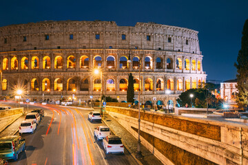 Naklejka na ściany i meble Rome, Italy. Colosseum Also Known As Flavian Amphitheatre In Evening Or Night Time. Night Traffic Light Trails Near Famous World Landmark.