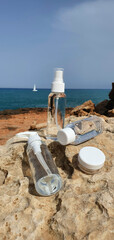 Fototapeta na wymiar Bottle for cosmetics without a label for advertising. Bottles for cosmetics on the background of the sea and stones. Advertising cosmetics in nature near the sea. Blank for advertising cosmetics.