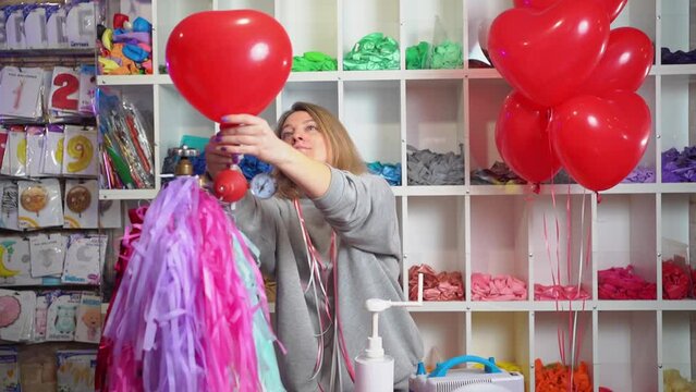 a woman inflates of helium from a balloon in the shape of a heart.
