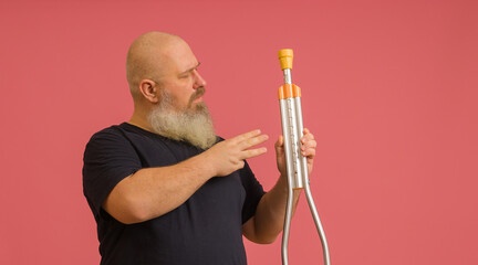 a man with a beard in a black T-shirt with a crutch in his hands on a colored background
