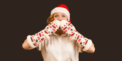 crazy woman in santa claus hat covered her mouth with her hands, black background