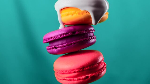 Close up of white glaze draining down the three macarons on a colorful wall background. Stock clip. Sweet food porn concept.