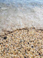 A small sea pebble in close-up. Seawater rushing onto a pebble beach