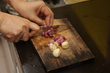 The cook cutting and dice onion on a wooden chopping board. Closeup