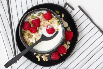 Overhead view of vanilla yogurt with granola and fresh raspberries; copy space