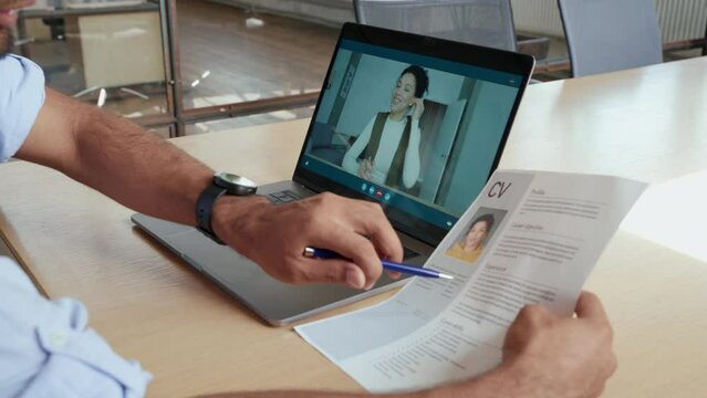 Indian human resource manager holding cv having virtual job interview conversation with remote female candidate during distant business video call on laptop computer. Online recruitment concept. 